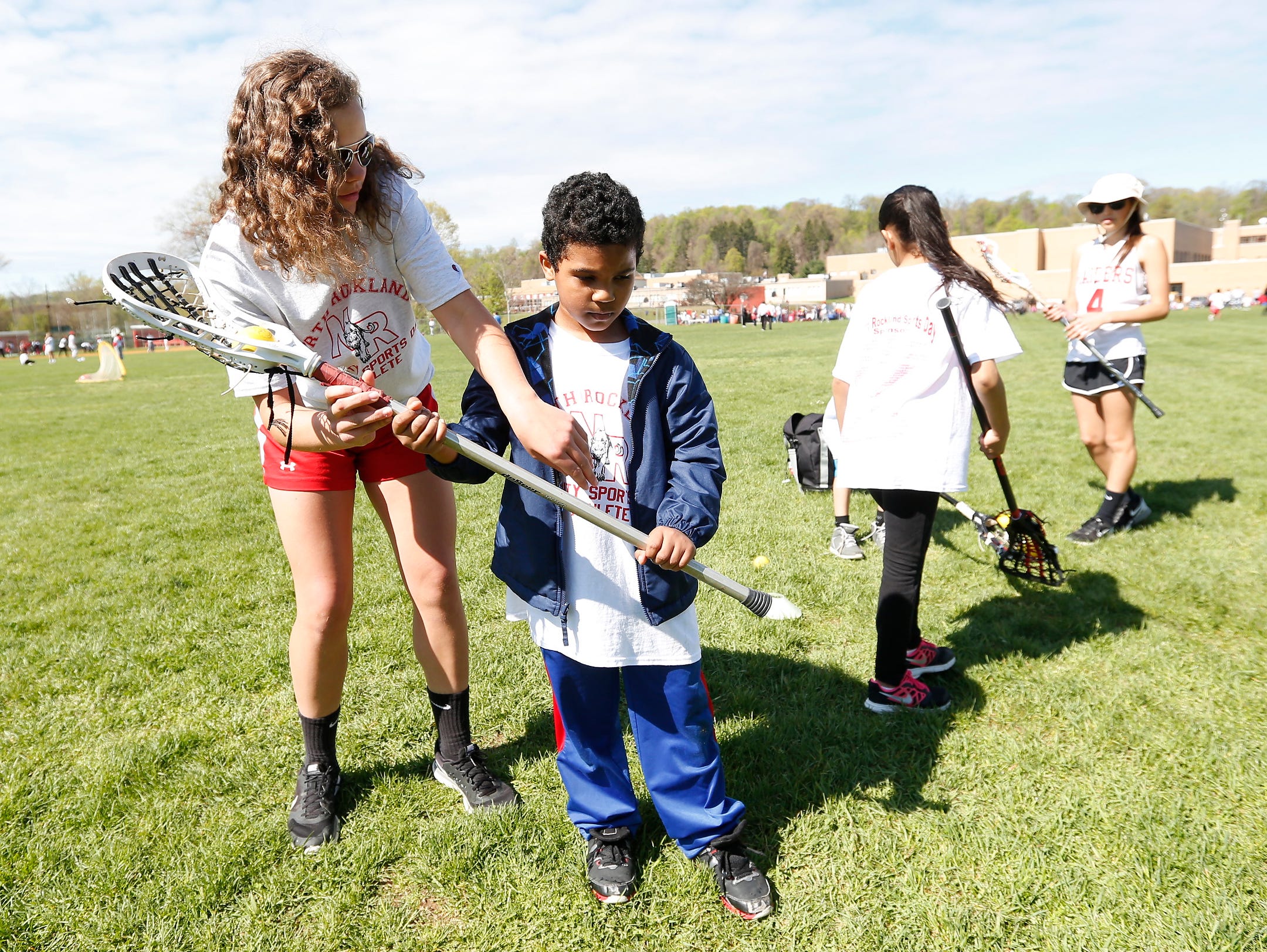 Junior varsity lacrosse player, Emily Cooney, left give a shooting lesson to Raymond Hilario-Saverino, 8, at the second annual "Sports Day for Charity" event at North Rockland High School in Thiells on Saturday, April 30, 2016.