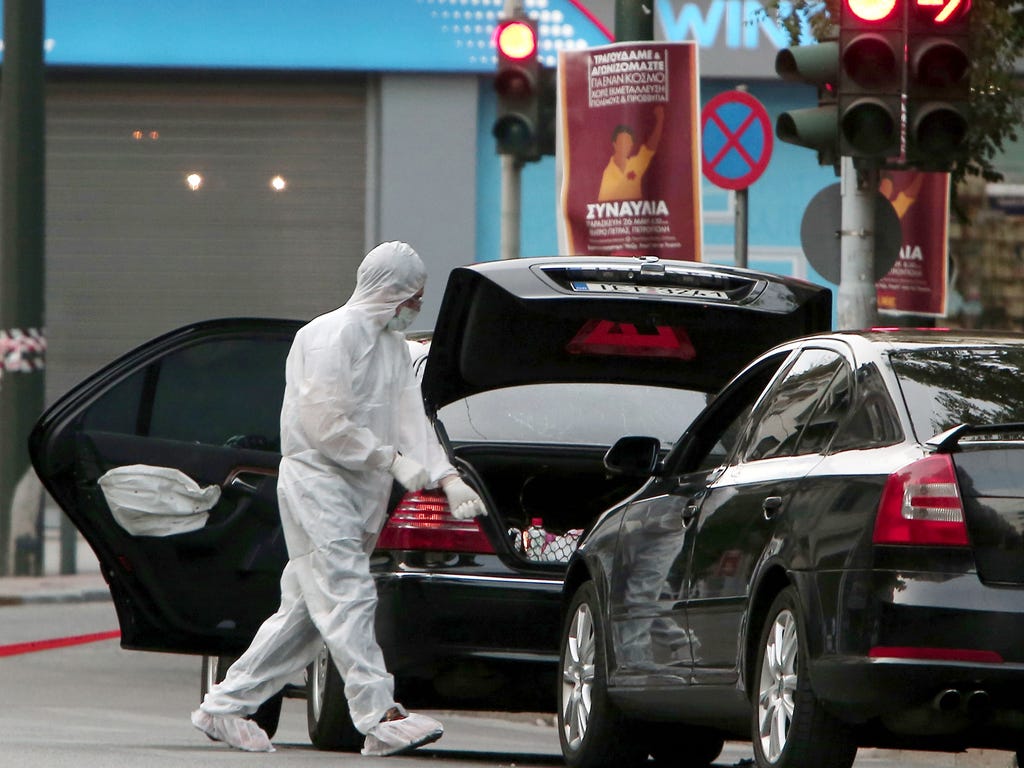 Forensic experts search for evidence in and around the car of Greek former prime minister Lucas Papademos in Athens after Papademos was hurt when an explosive device went off inside his car. \u000dState news agency ANA said Papademos was undergoing s