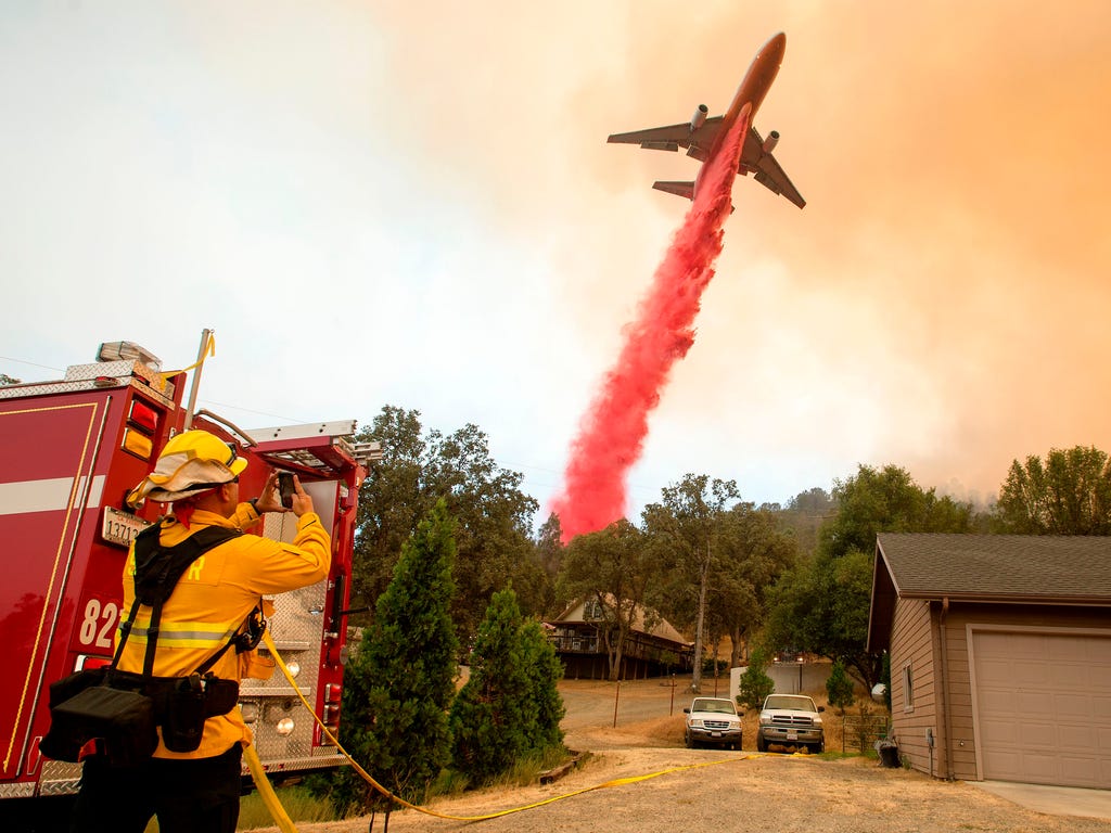 An air tanker drops fire retardant on flames as firefighters continue to battle against the Detwiler fire in Mariposa, Calif.