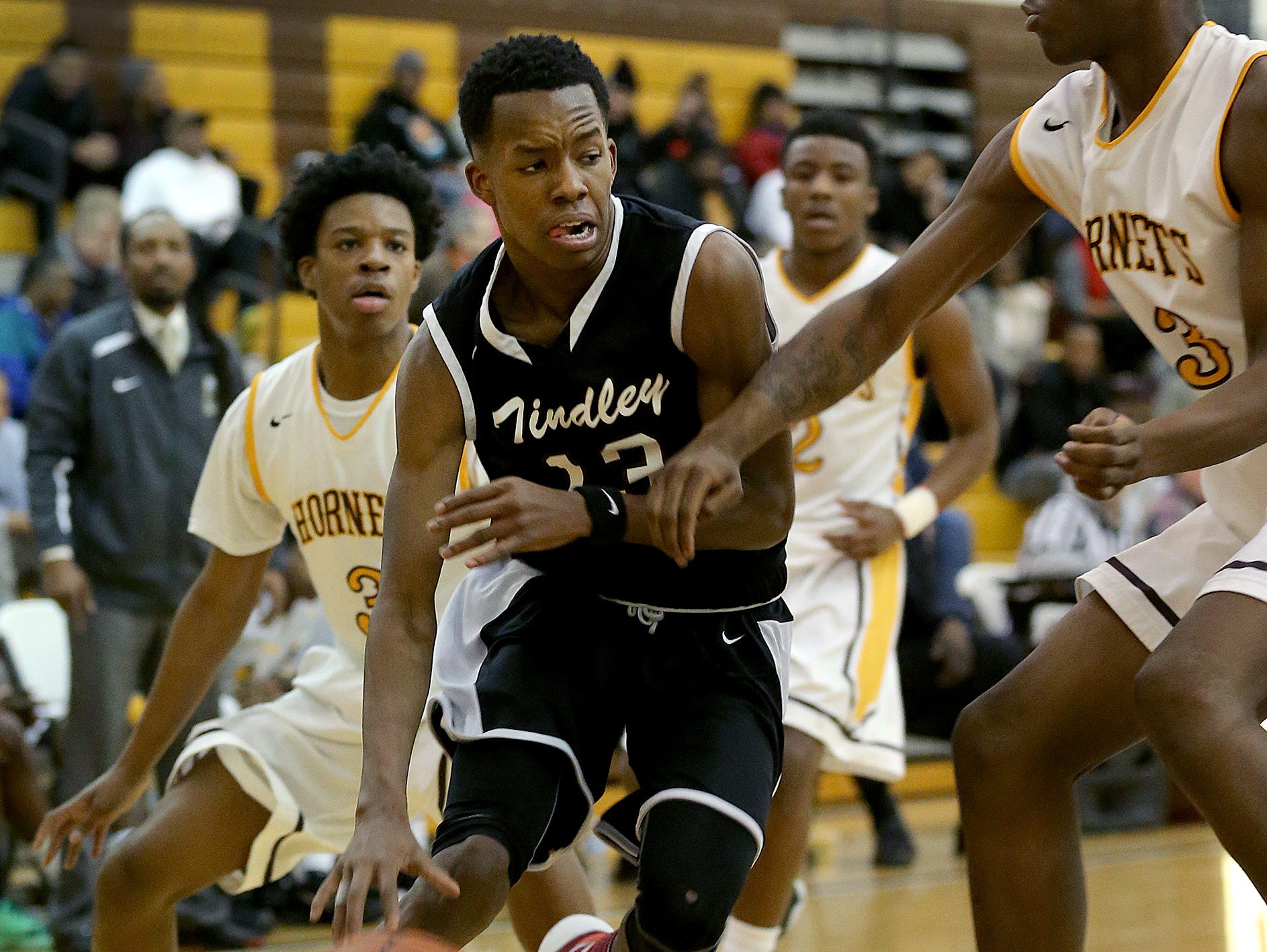 Tindley Tigers Eric Hunter (13) drives by Howe Hornets David Burns (43) and Jermaine Couch (3) in the first half of their Indianapolis City Boys Basketball Tournament Thursday, Jan 21, 2016, evening at Thomas Carr Howe High School.