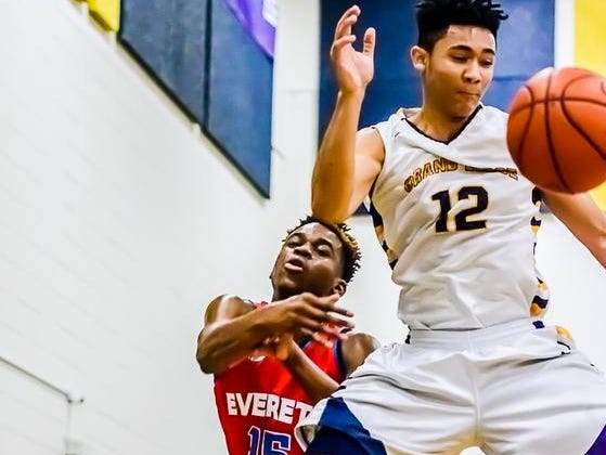 Marquez Gordon ,15, of Everett flips the ball back in bounds as he and Josh Horford ,12, of Grand Ledge leap to save the ball during their game Friday.