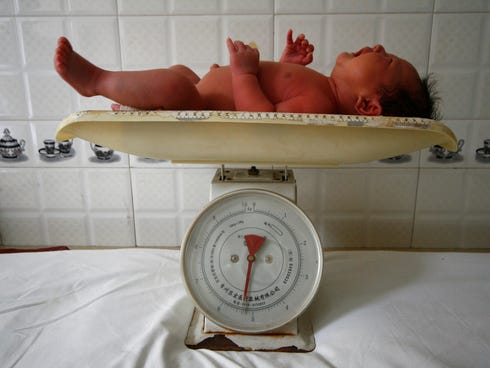 A baby cries on a weighing scale at a local hospital in Suining, in southwest China's Sichuan province.