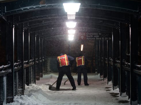Workers clear snow from a pedestrian passageway at the Astoria Blvd. subway station on Friday in the Queens borough of New York.