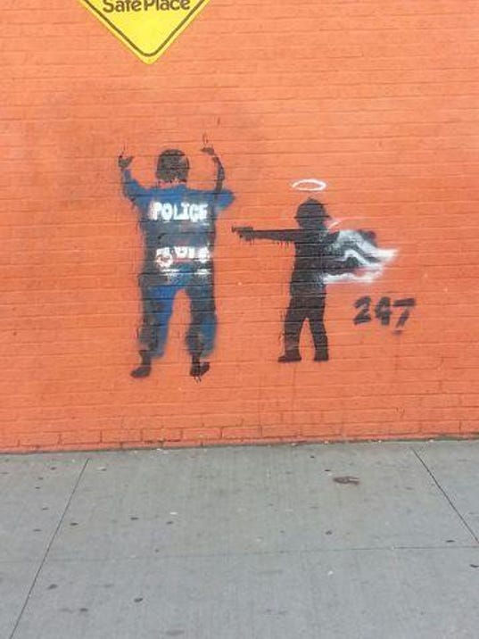 Excellent: Graffiti of angel pointing gun at police B9315697301Z.1_20141231120811_000_GLR9I88JJ.1-0