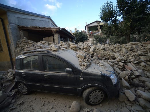 A car lies under a damaged wall after a strong quake