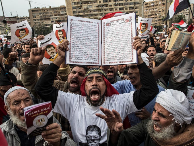 A man holds up a Quran as supporters of Egyptian President Mohammed Morsi and members of the Muslim Brotherhood chant slogans during a rally on Dec. 14, 2012, in Cairo.  Opponents and supporters of Morsi staged rallies before a referendum vote on the country's draft constitution that was rushed through parliament in an overnight session on Nov. 29.