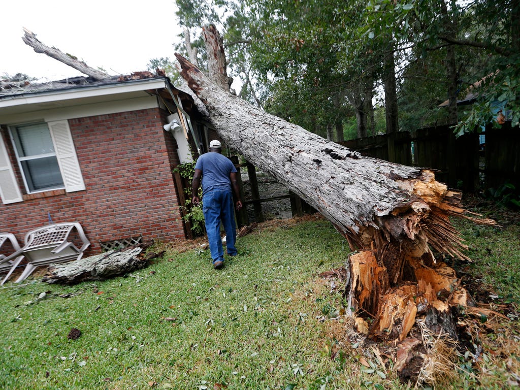 Lawrence Carriere checks on the home of his neighbor after a tree fell on it and crashed through the roof, in Biloxi, Miss., in the aftermath of Hurricane Nate, Oct. 8, 2017.