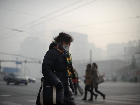A woman wearing a face mask makes her way along a street in Beijing on Jan. 16, 2014.