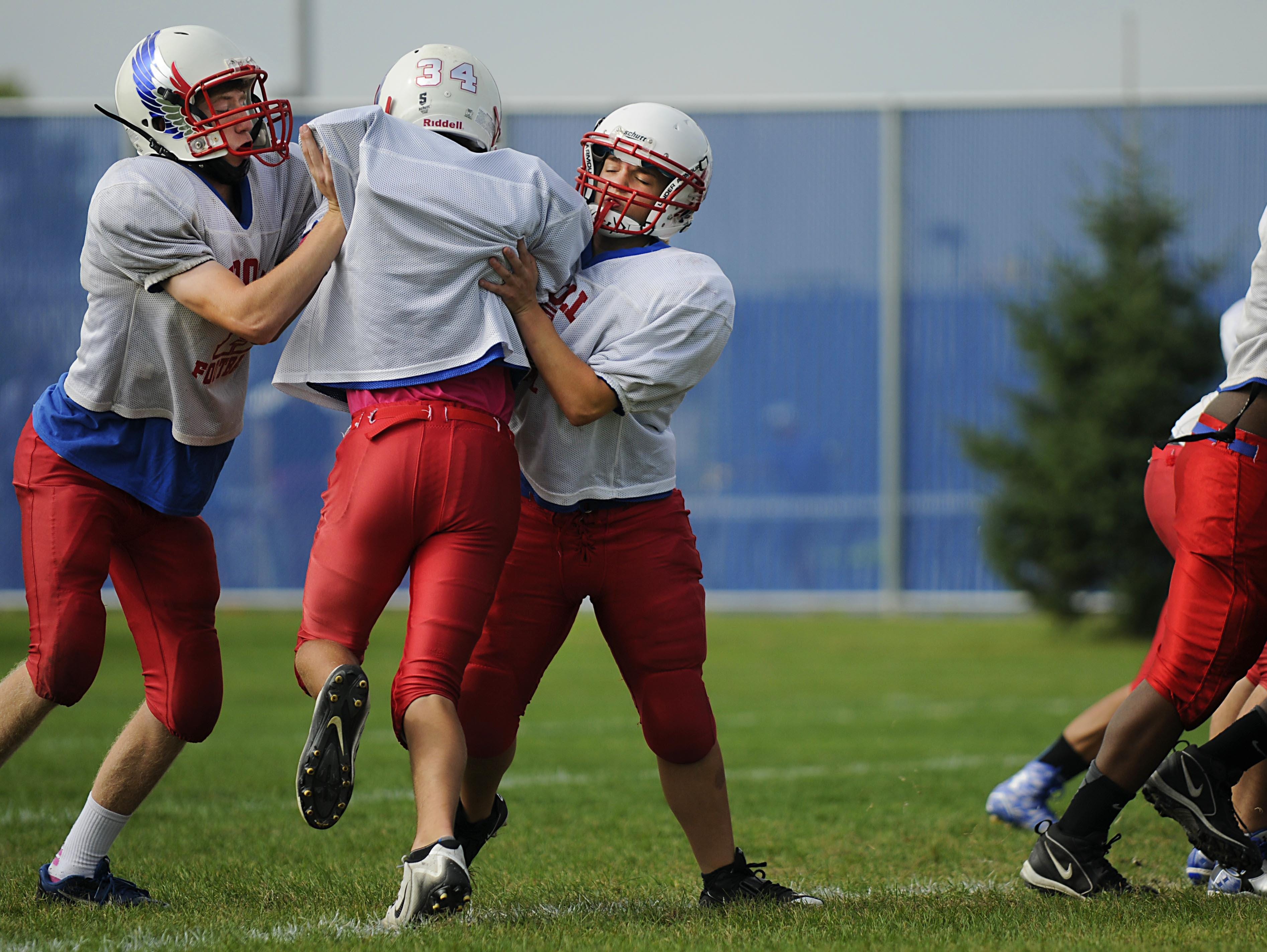 Tight end receiver Jake Reber and linebacker Angie Stolt block wide receiver Peyton Joos at practice on Wednesday at Apollo High School.