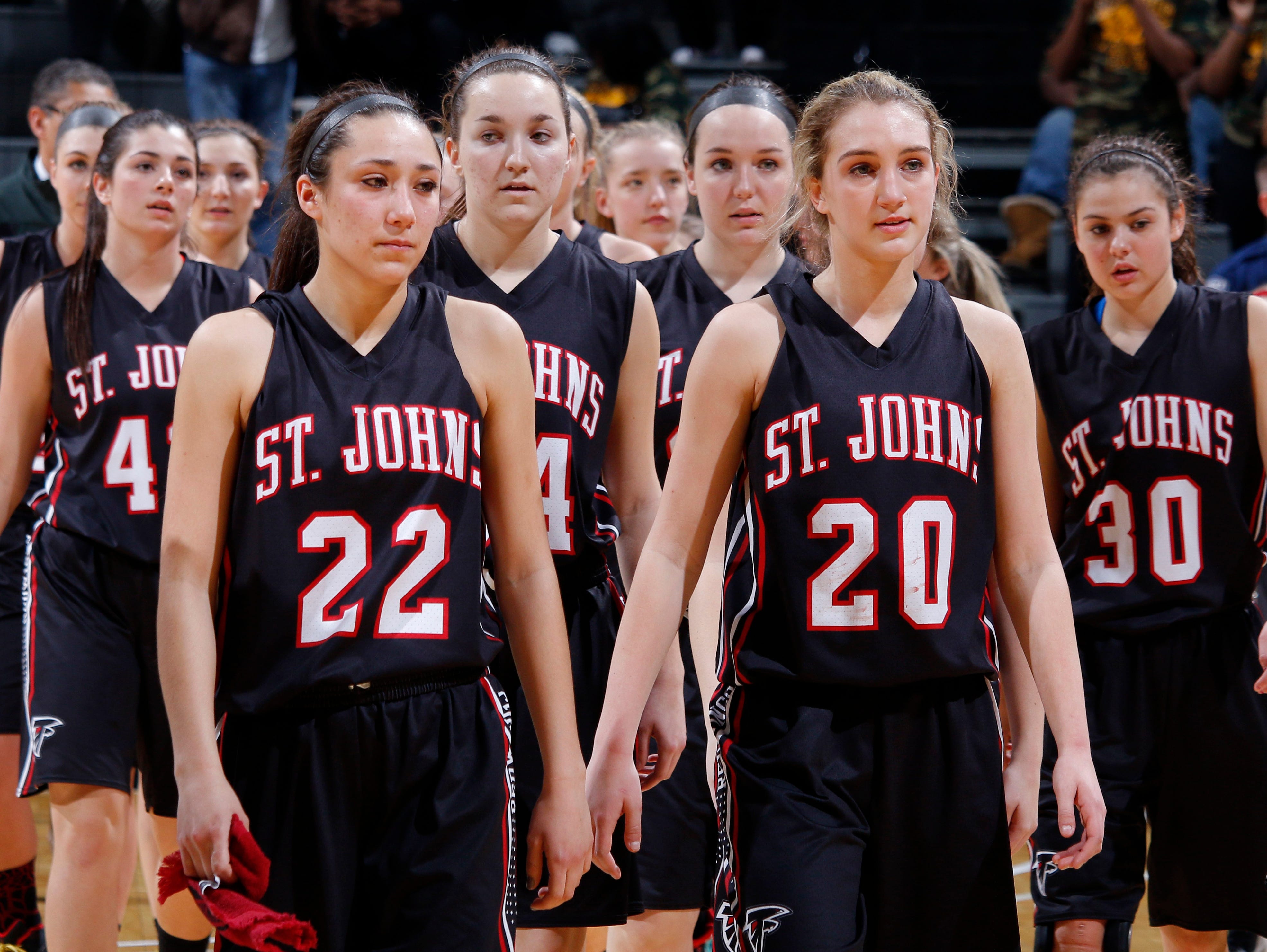 St. Johns players, including Erika Ballinger (22) and Maddie Maloney (20), walk off the court following their loss to Detroit King in their MHSAA Class A semifinal game Friday, March 18, 2016, at the Breslin Center in East Lansing. St. Johns fell 56-48.