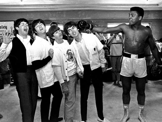 In this Feb. 18, 1964, file photo, The Beatles -- from left, Paul McCartney, John Lennon, Ringo Starr, and George Harrison -- take a fake blow from Cassius Clay, who later changed his name to Muhammad Ali,  while visiting the heavyweight contender at his training camp in Miami Beach, Fla.