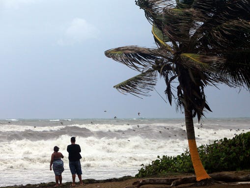 A couple looks out at a rough sea as Tropical Storm