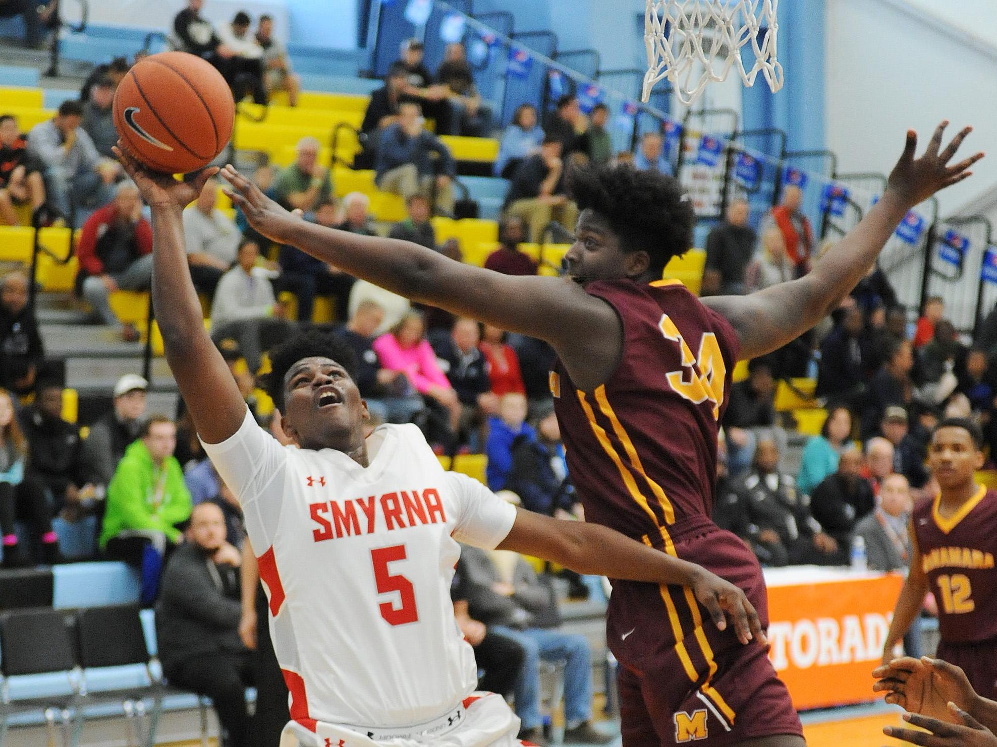 Smyrna's #5 Jaymeir Garnett gets 2 points as Bishop McNamara'a Makhel Mitchell attempts block as The Annual Slam Dunk to the Beach Basketball Tournament started at Cape Henlopen High School in Lewes on Tuesday December 27th with Smyrna HS (white) hosting Bishop McNamara HS from Forestville, Md.