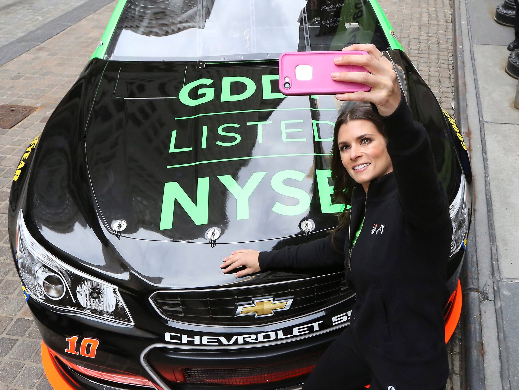epa04688909 Auto race driver and Go Daddy advertising spokeswoman Danica Patrick, shoots a self portrait of her and her race car outside the New York Stock Exchange after arriving for the Initial Public Offering of Go Daddy stocks, GDDY, in New York,