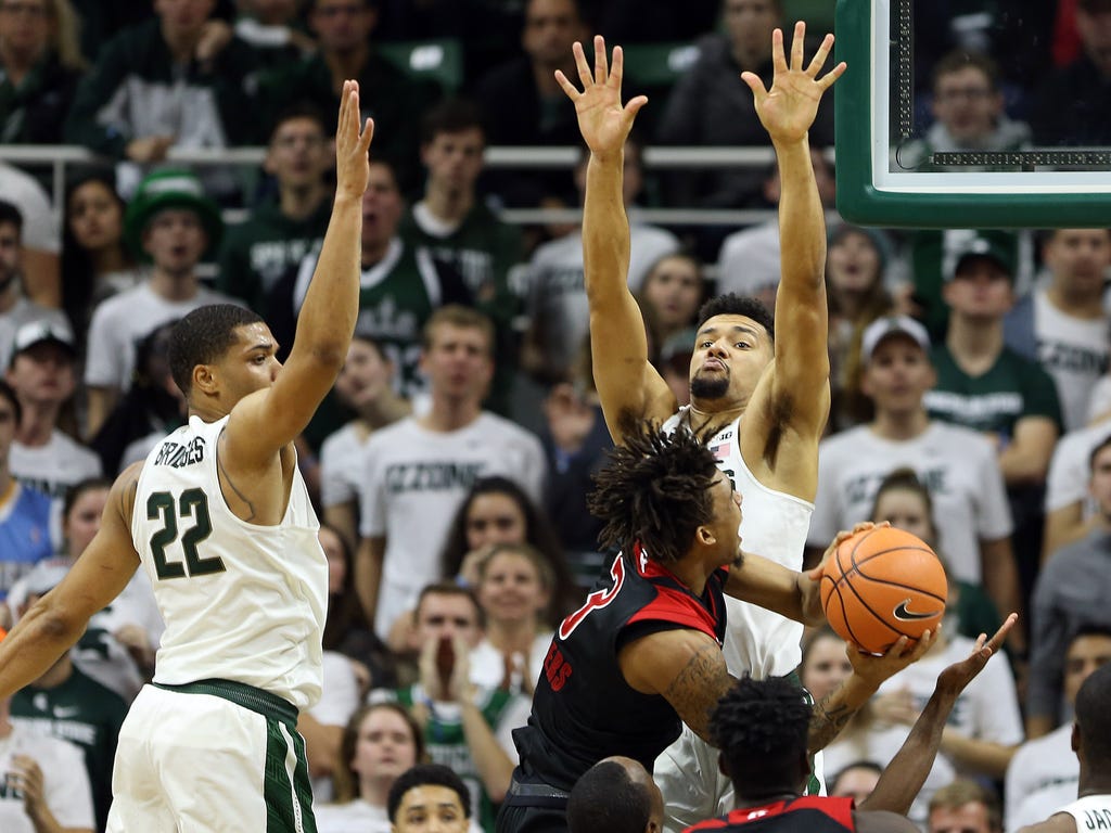 Rutgers Scarlet Knights guard Corey Sanders is defended by Michigan State Spartans forward Kenny Goins, right, and guard Miles Bridges during the second half of a game at Jack Breslin Student Events Center in East Lansing, Mich.