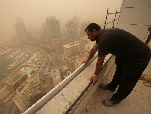 A Syrian worker  looks down from the rooftop of a high-rise