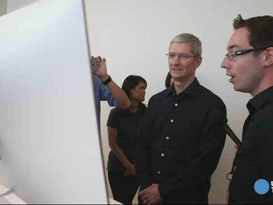 Apple CEO Tim Cook looks at the new iMac