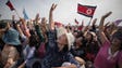 Spectators cheer as parachutists perform an aerial