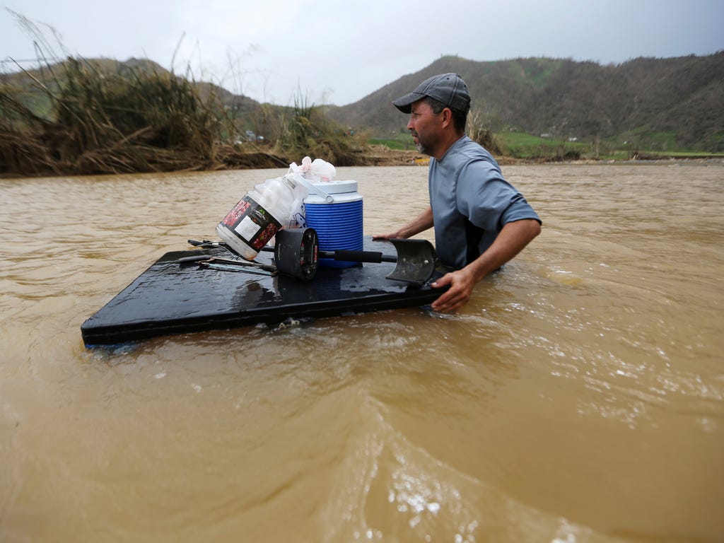 Manolo Gonzales crosses through the Rio San Lorenzo de Morovis, since the bridge that crosses the river was swept away by Hurricane Maria, in Morovis, Puerto Rico.