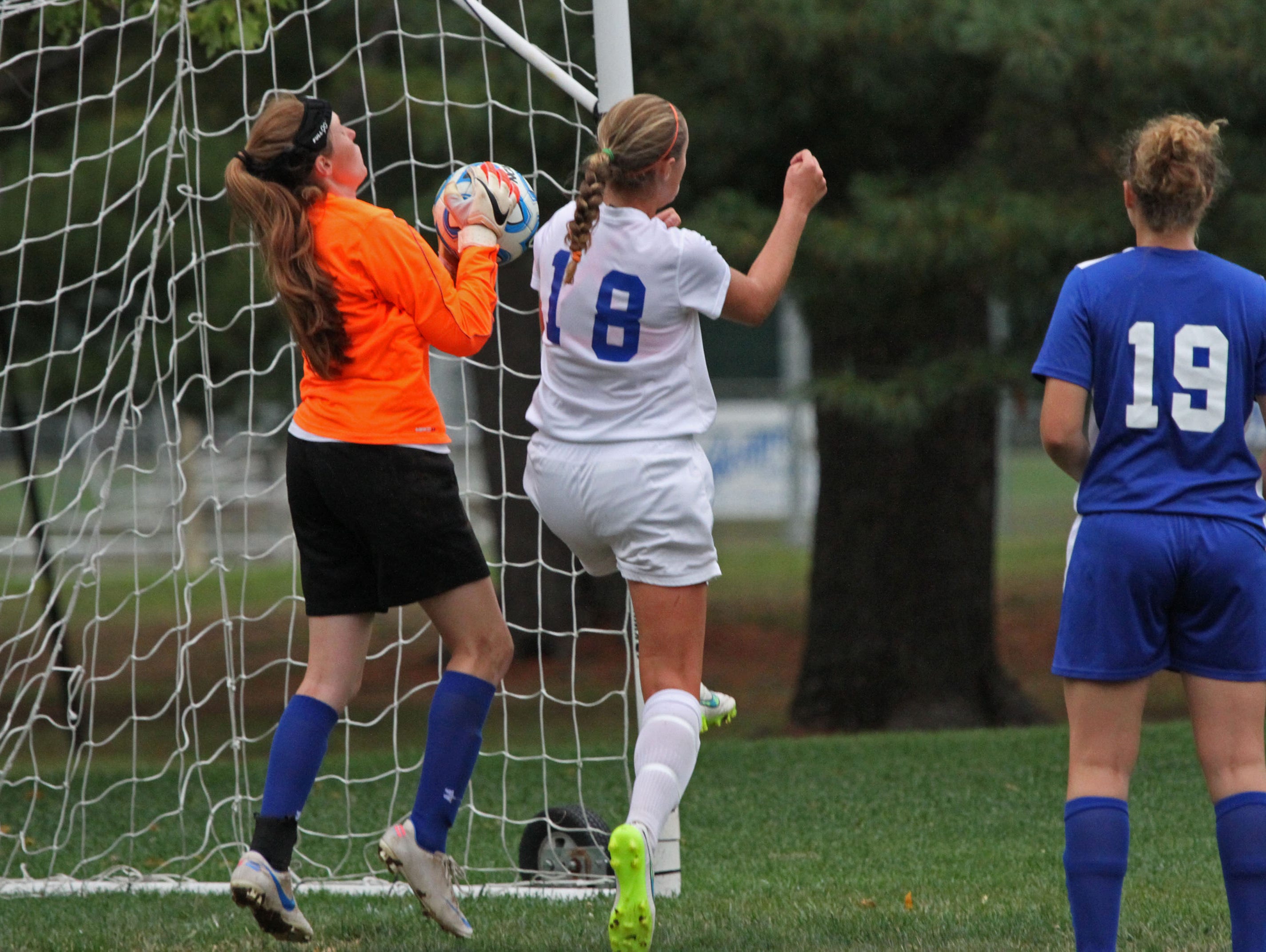 Metuchen goalie Emily Buchanan makes a save in girls soccer game at Middlesex. On offense is Mackenzie Meixner (18) for Middlesex.