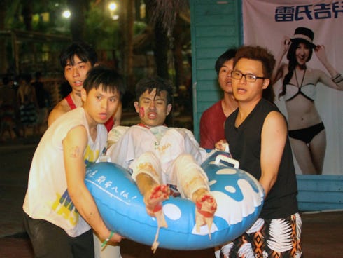 People carry an injured man at the Formosa Fun Coast amusement park after an explosion in the Pali district of New Taipei City on June 27, 2015.