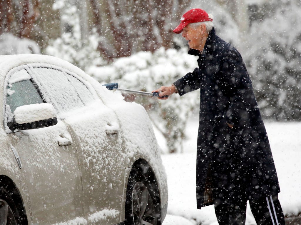 A Jackson, Miss., resident wipes snow off the windows of a vehicle as a heavy morning snow falls. The forecast called for a wintry mix of precipitation across several Deep South states.
