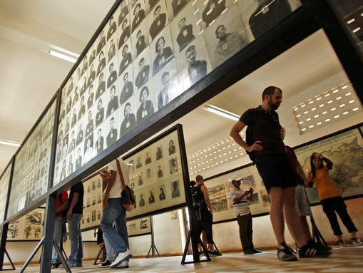 Tourists view portraits of victims executed by the