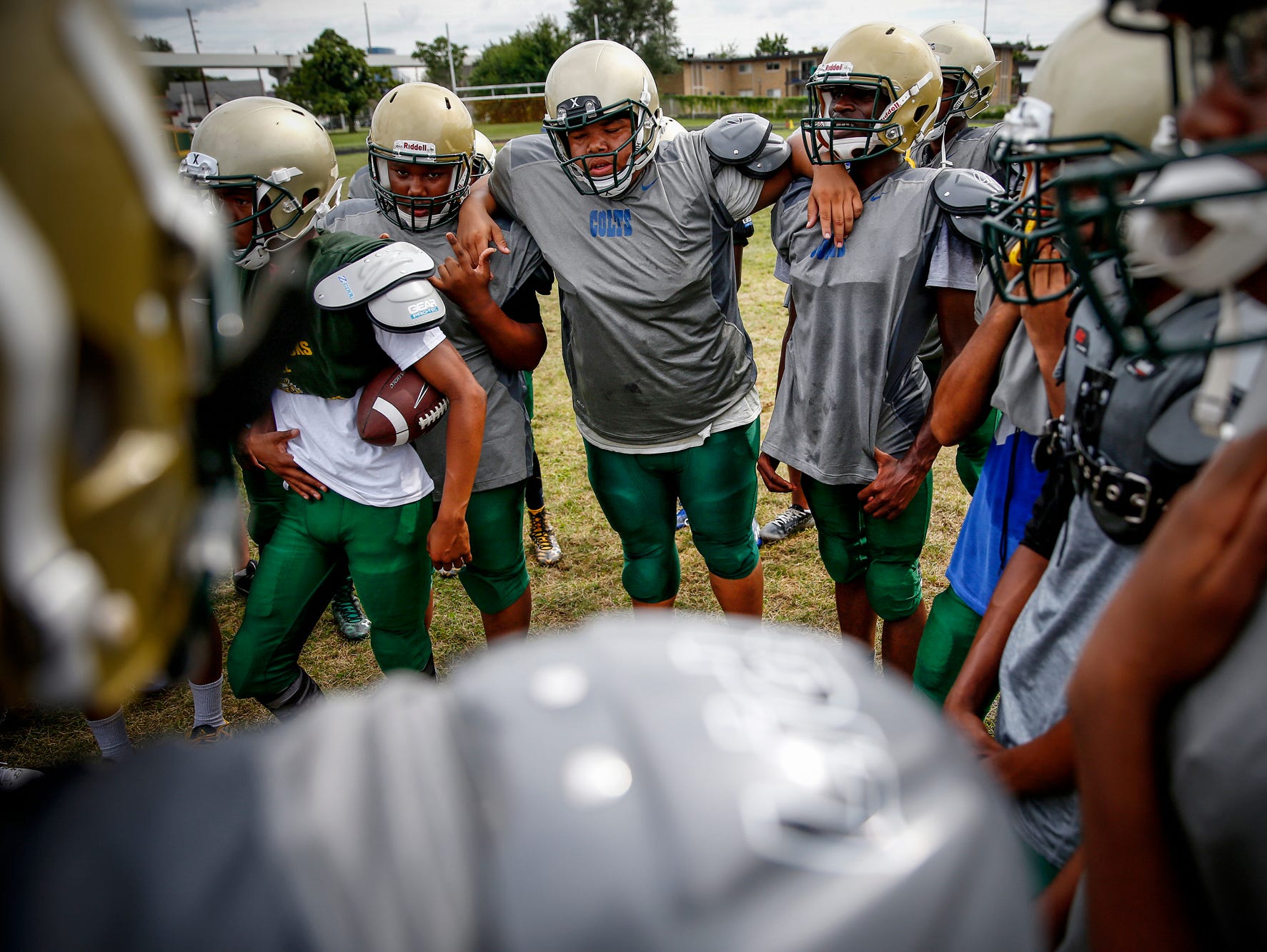 Exhausted Crispus Attucks players lean on each others shoulders during a team huddle during practice at Alonzo Watford Athletic Field on Aug. 17, 2016.