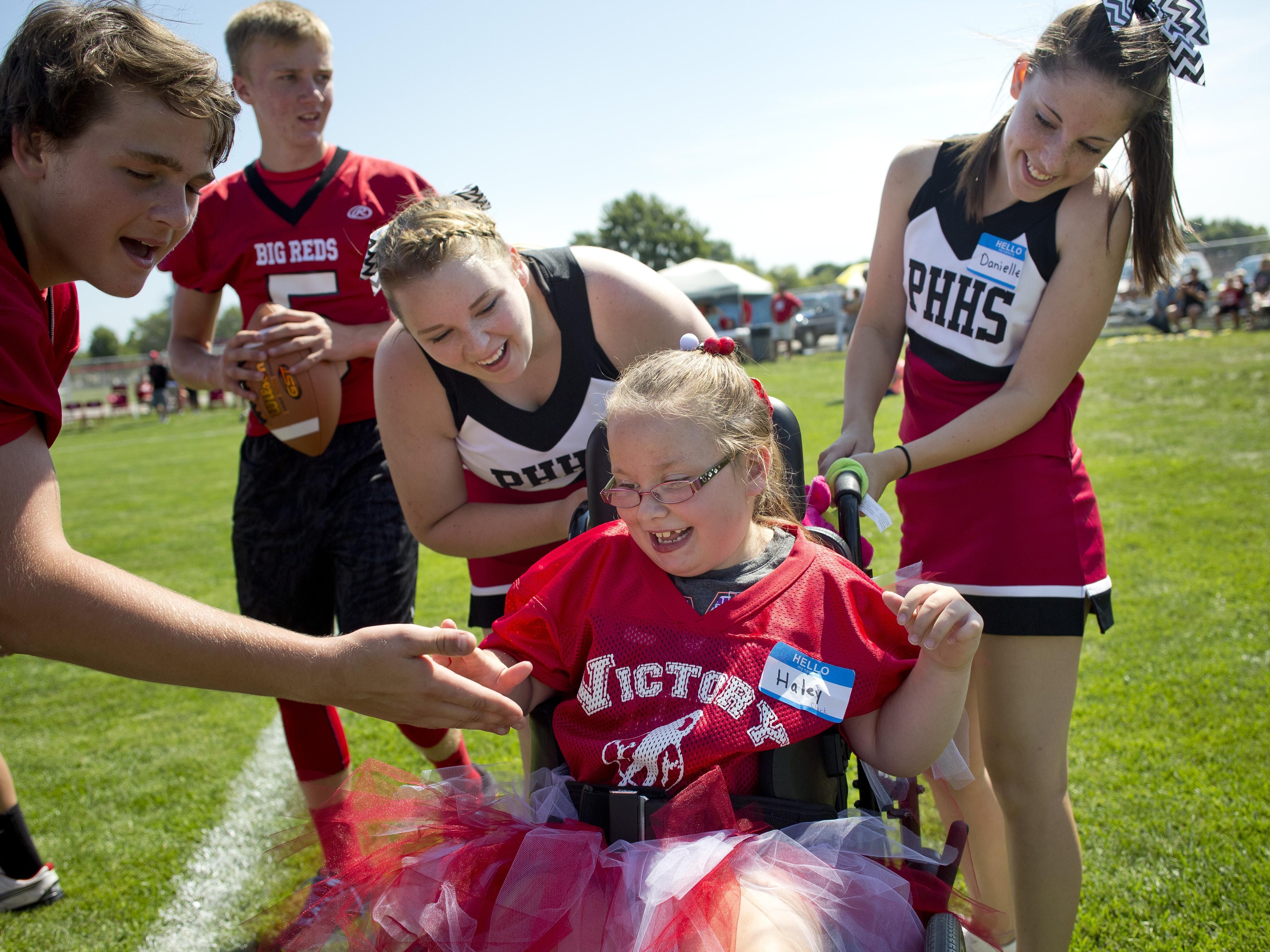 Haley Clark gets high-fives after she scored a touchdown with her mentors Tiffany Peyerk and Danielle Stockwell during Victory Day Saturday, August 15, 2015 in Memorial Stadium at Port Huron High School. The event paired special needs students with mentors from the football and cheerleading teams.