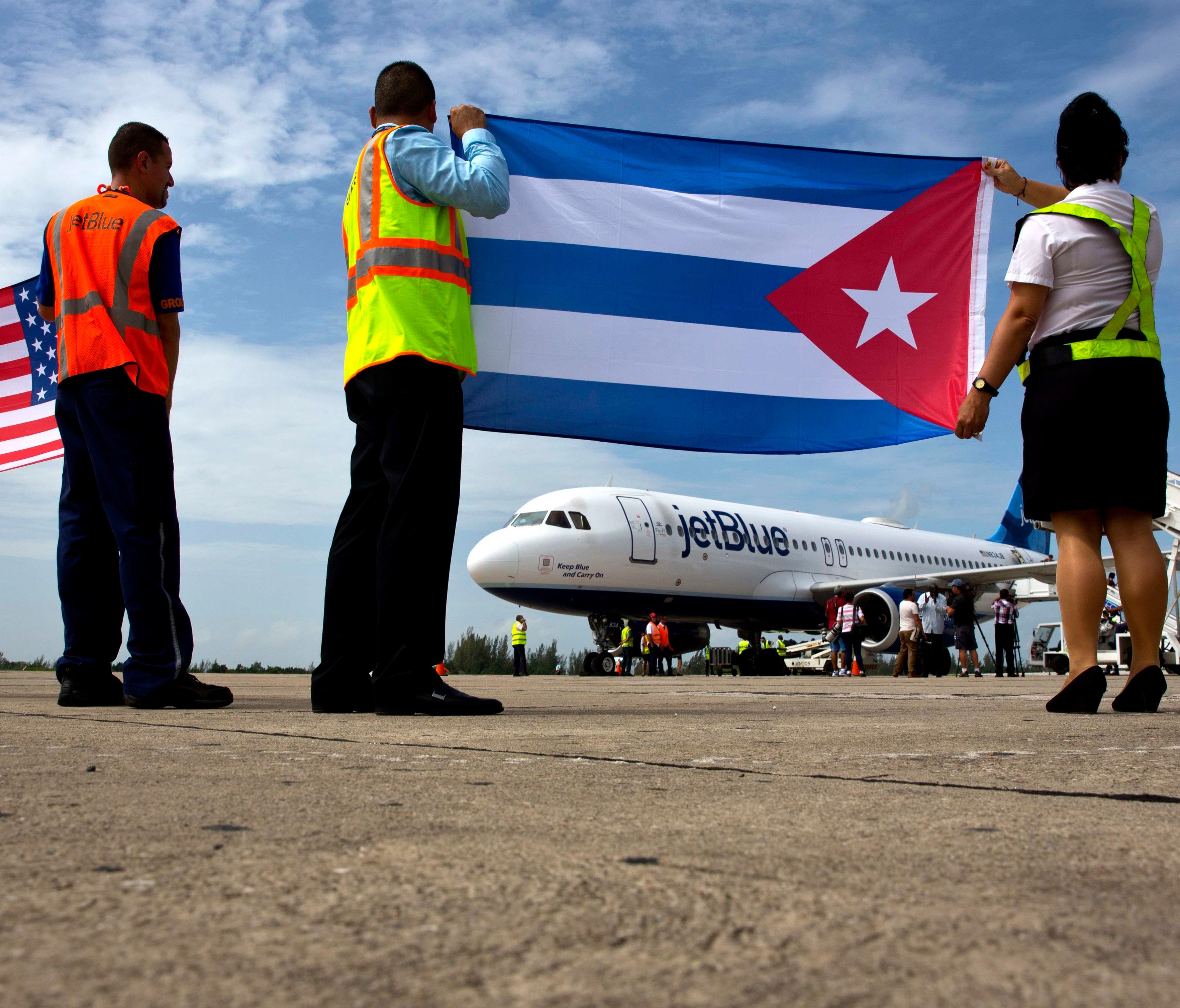 Airport workers receive the JetBlue flight 387 holding the United States and Cuban national flags on the airport tarmac in Santa Clara, Cuba.