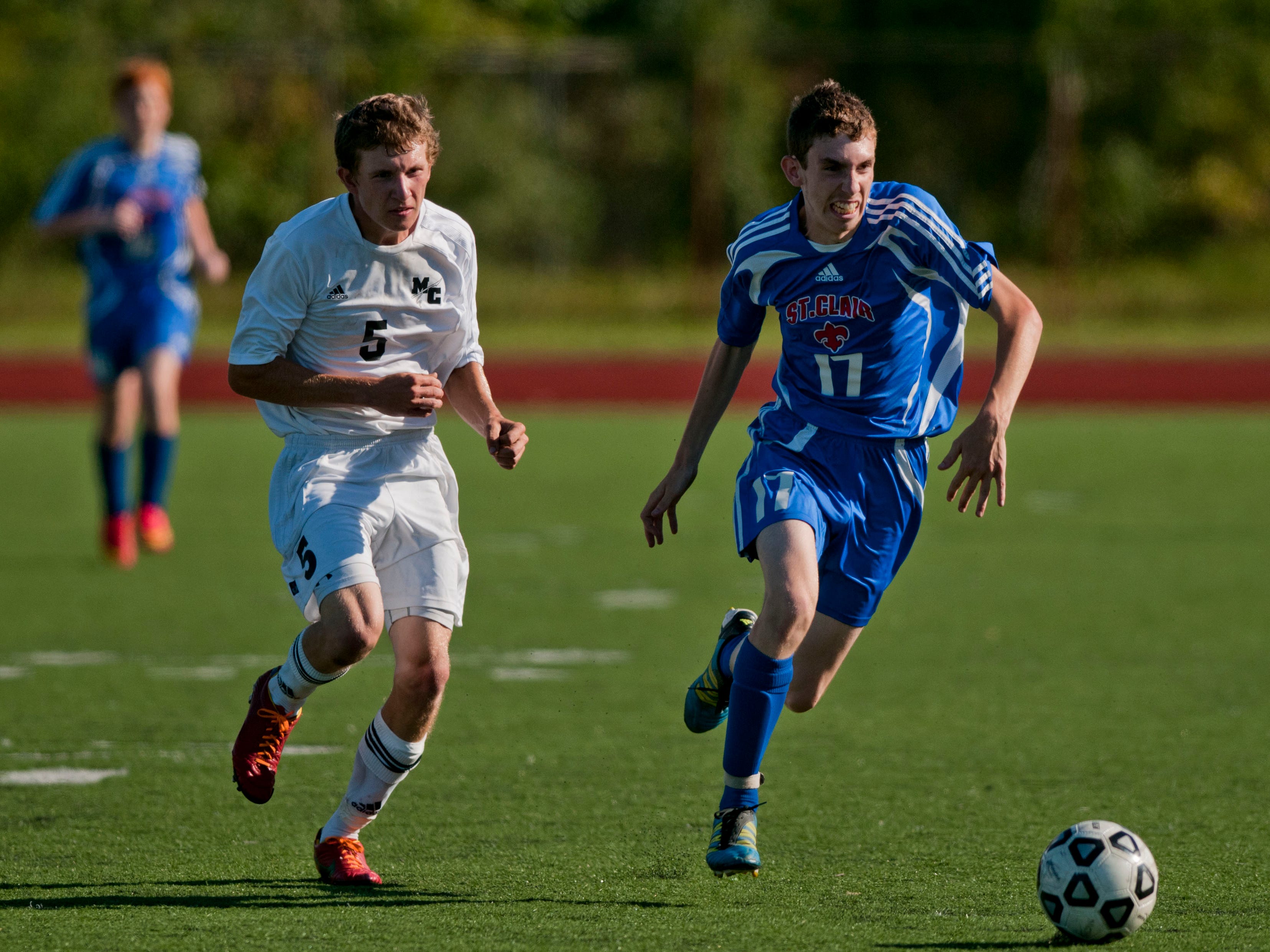 St. Clair senior Chris McCollum drives the ball down field as Marine City senior Billy Wesler chases during a soccer game August 27, 2014 at East China Stadium.