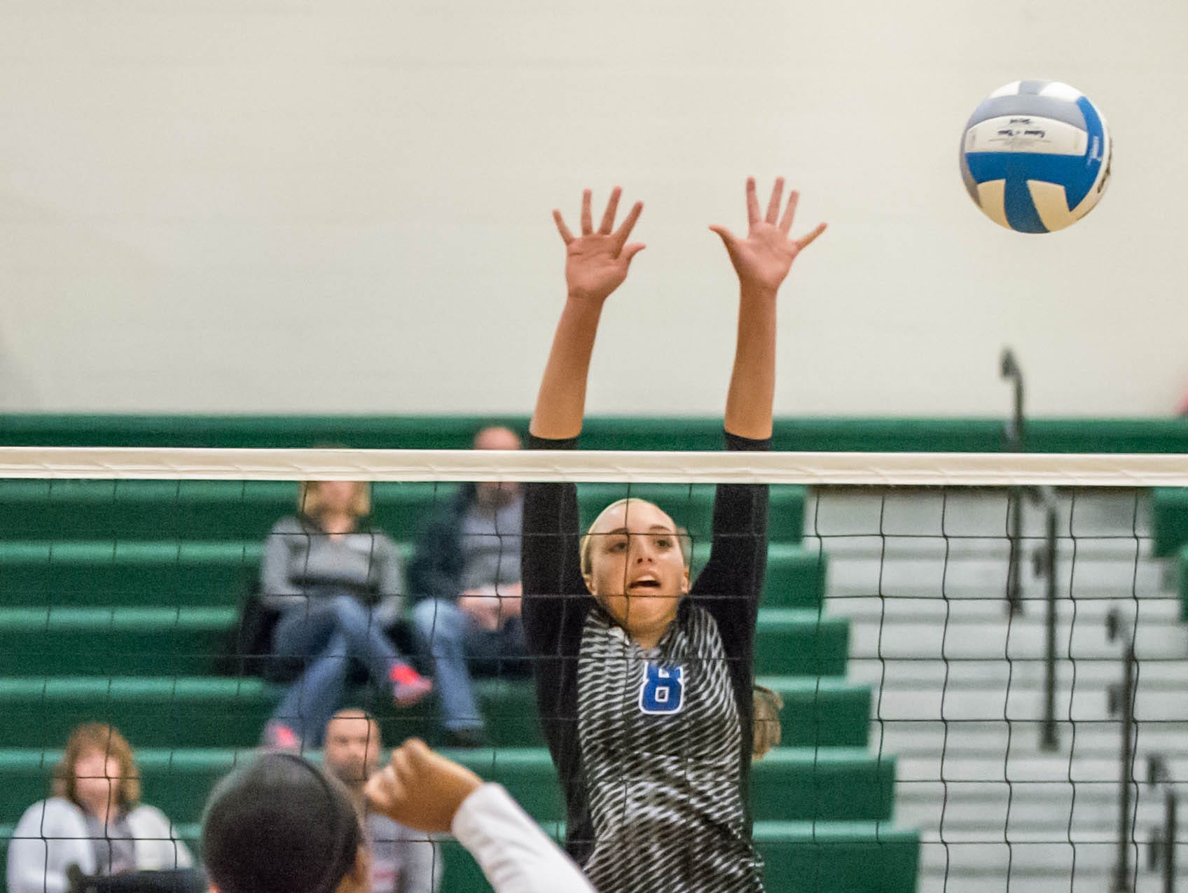 Harper Creek's Charley Andrews (8) goes for the block over Battle Creek Central's Jamilah Wade (4) at the All-City volleyball tourney on Saturday.