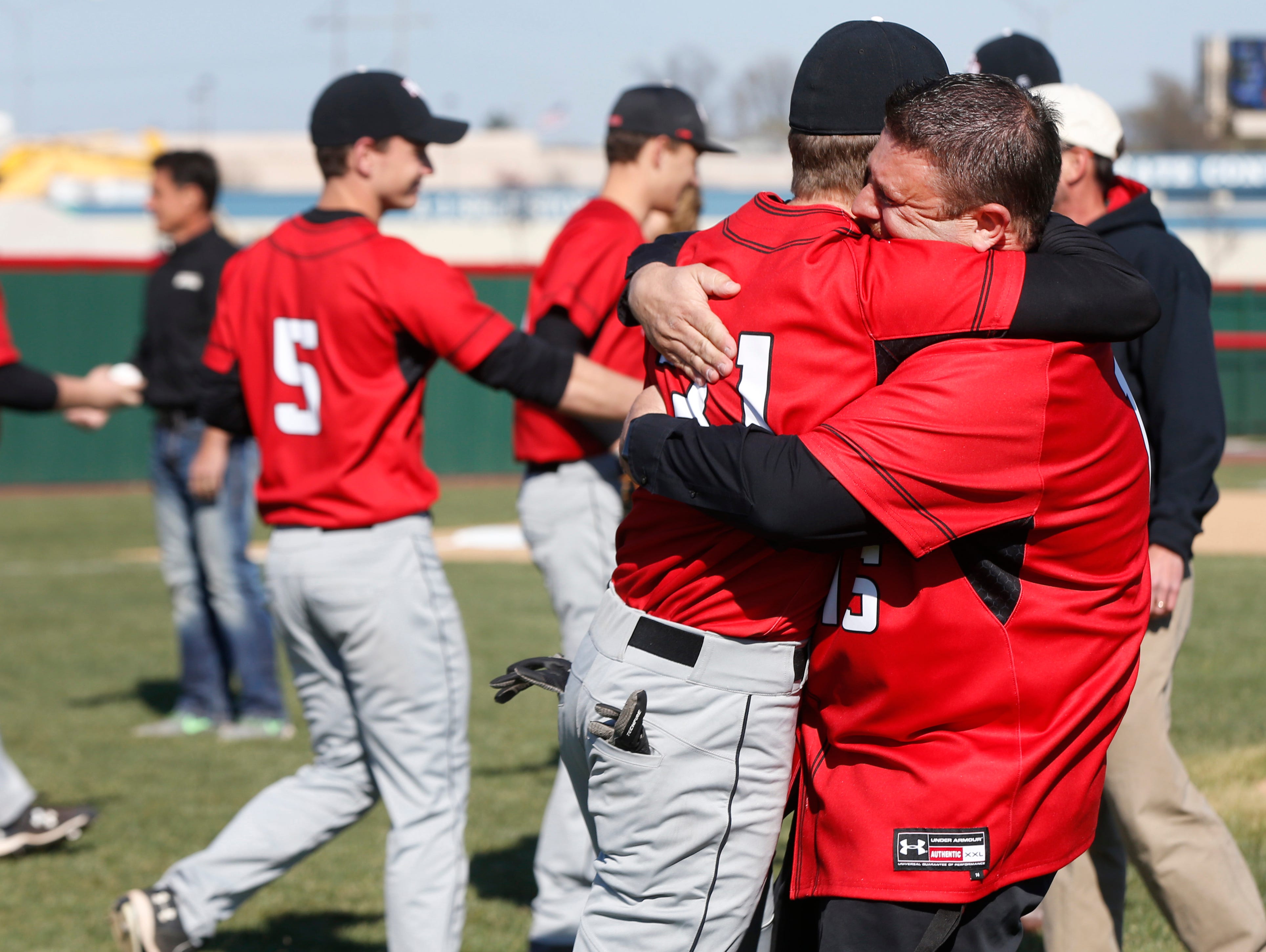 Matt Searson hugs his son Matthew Searson after he threw out the first pitch before the New Covenant Academy baseball team played their first game at Federal Protection Field on Monday, Mar. 21, 2016.