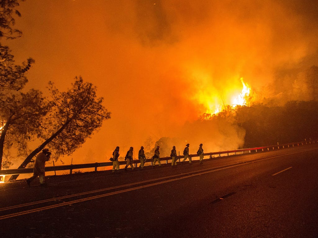 Cal Fire firefighters walk along Highway 20 as the Rocky fire burns near Clear Lake, Calif. The fire has charred more than 27,000 acres, and is currently only 5% contained.