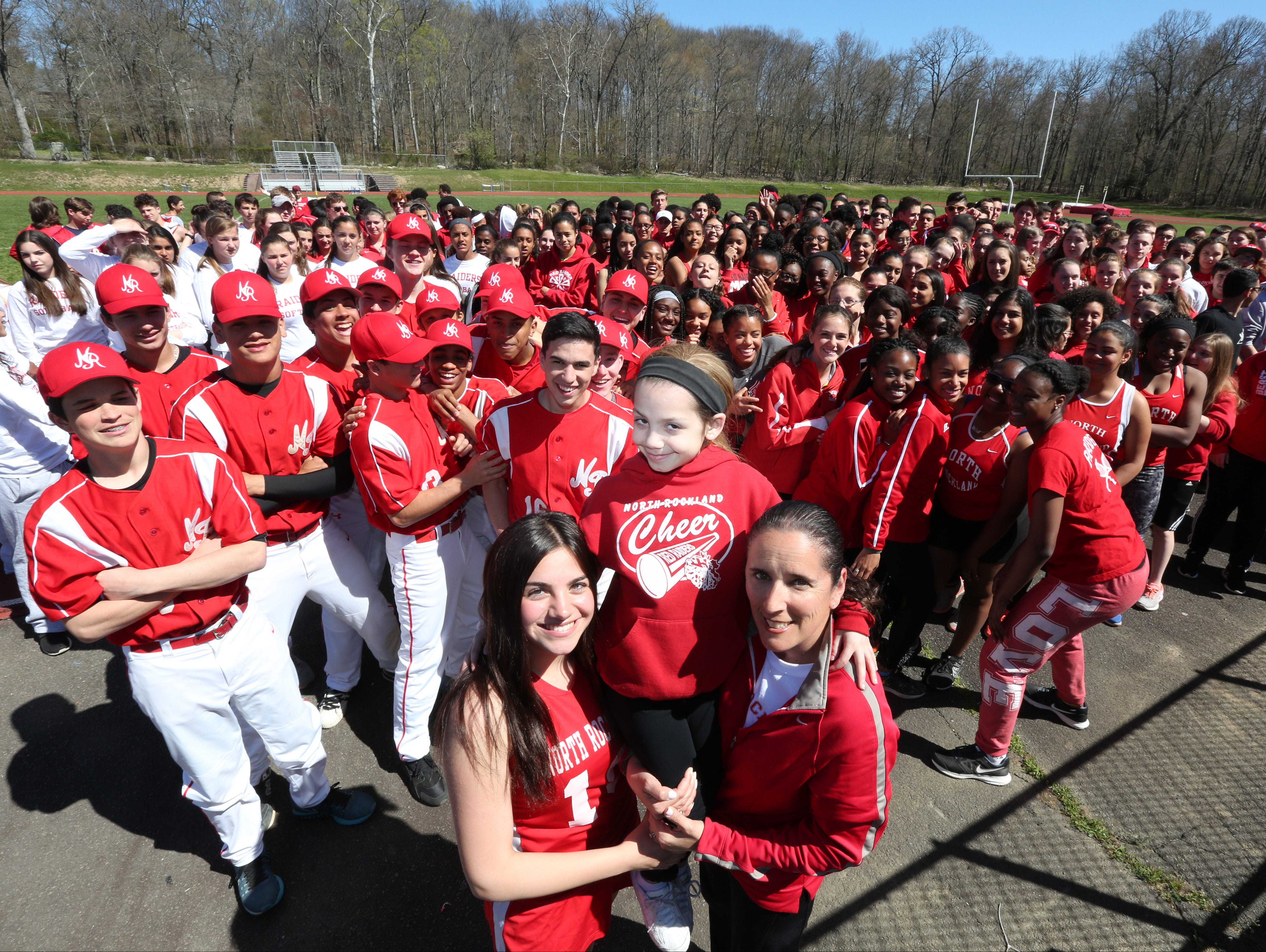 Athletes gather behind Stony Point Elementary third-grader Gabby DiCarlo, who is being held up by her sister, Isabella DiCarlo and Jennifer LaBier, Stony Point Elementary teacher and high school tennis coach, at North Rockland High School April 20, 2016. They got together to spread the word about the second annual "Sports Day" at the high school on April 30. So far they have raised $14,000 for cancer and cystic fibrosis.