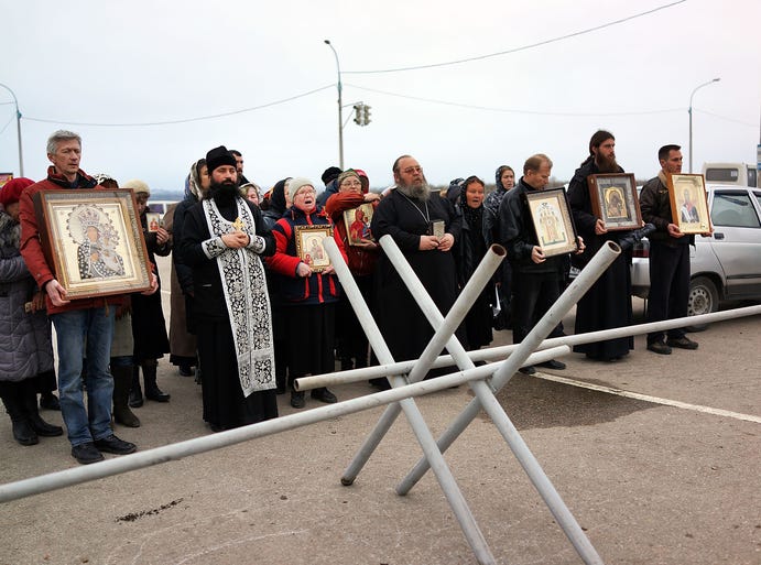 Members of an Orthodox church participate in a prayer vigil outside a Russian military checkpoint near a Ukrainian air force base that has reportedly been seized by the Russian military in Belbek, Ukraine.