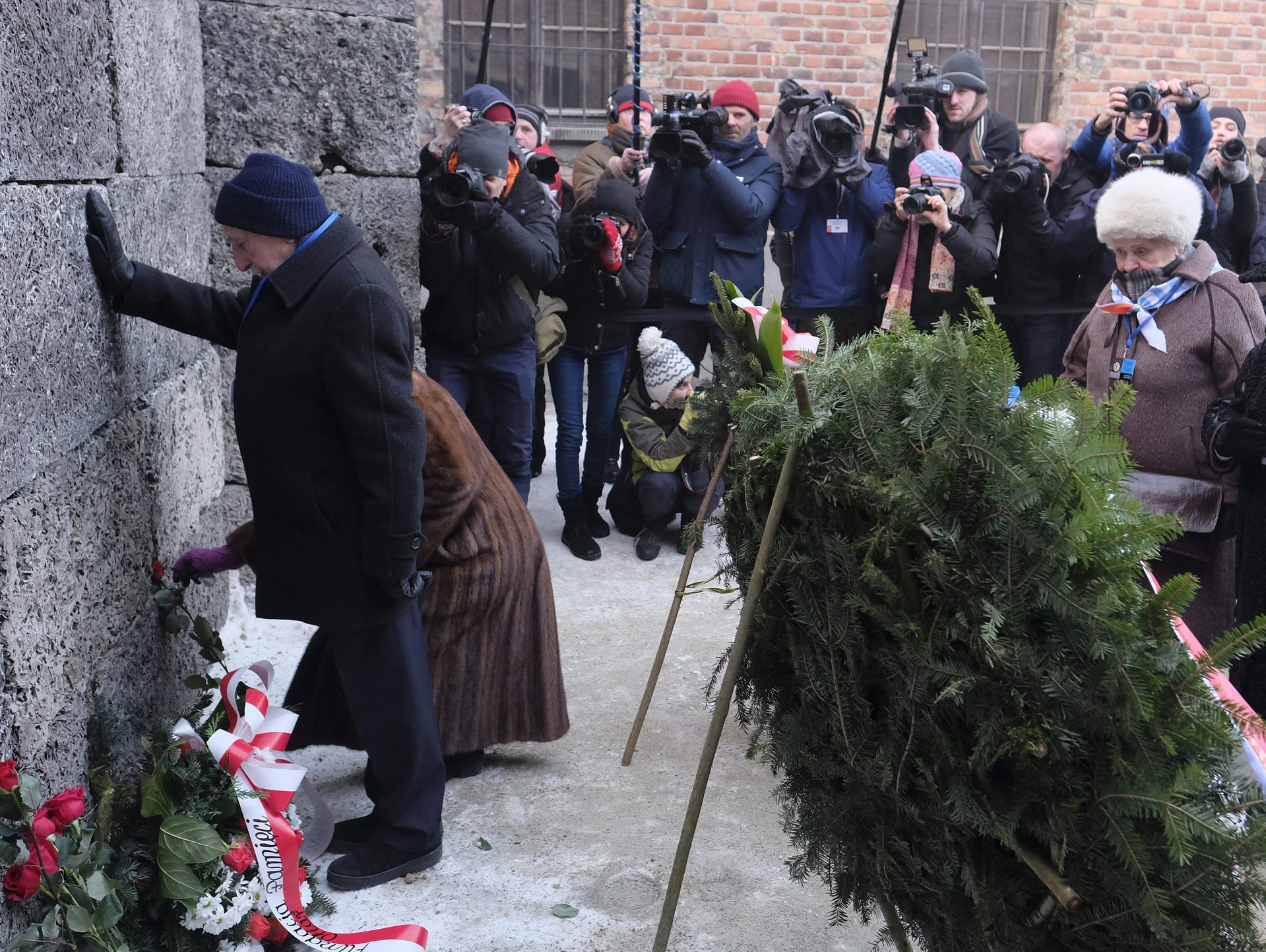 Former prisoners place candles and flowers at the Death