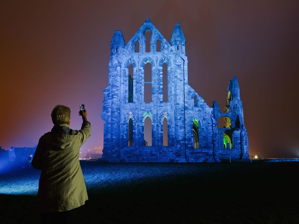 A woman takes a picture as a light display illuminates the historic Whitby Abbey in Whitby, England. The famous Benedictine abbey will be illuminated over four nights to coincide with Halloween and the popular Whitby Goth Weekend. The Abbey was part 
