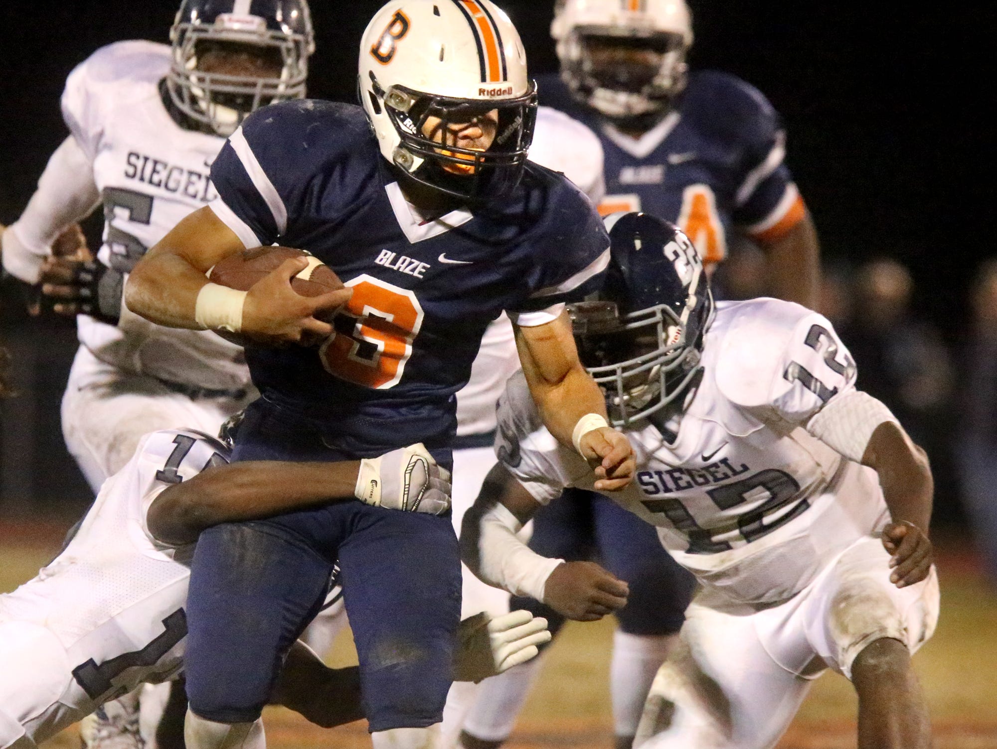 Blackman's Taeler Dowdy (3) is tackled by Siegel's Justin Perry (15) and Gef Elder (12) on Friday.