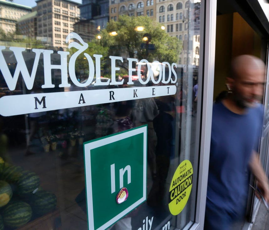 In this June 24, 2015, file photo, a shopper leaves a Whole Foods Market store in Union Square in New York.  Last month, the  high-end grocer opened a store in Chicago's Englewood neighborhood, one of the city's poorest neighborhoods.