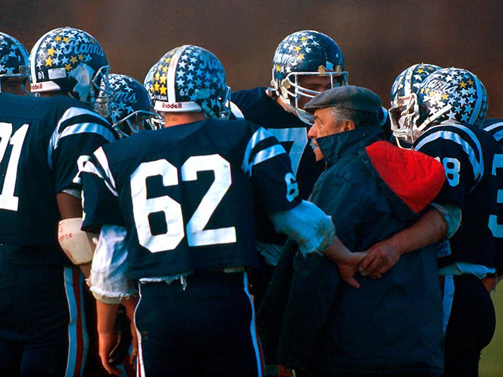 In a photo taken November 11, 1990 at John Bauer Sr's last football game, players gather around the coach for a pep talk during a time out. Bauer, the legendary Ram coach for 25 years, passed away 17 days before the championship game vs. Montclair. He was replaced by his son, John Bauer Jr.