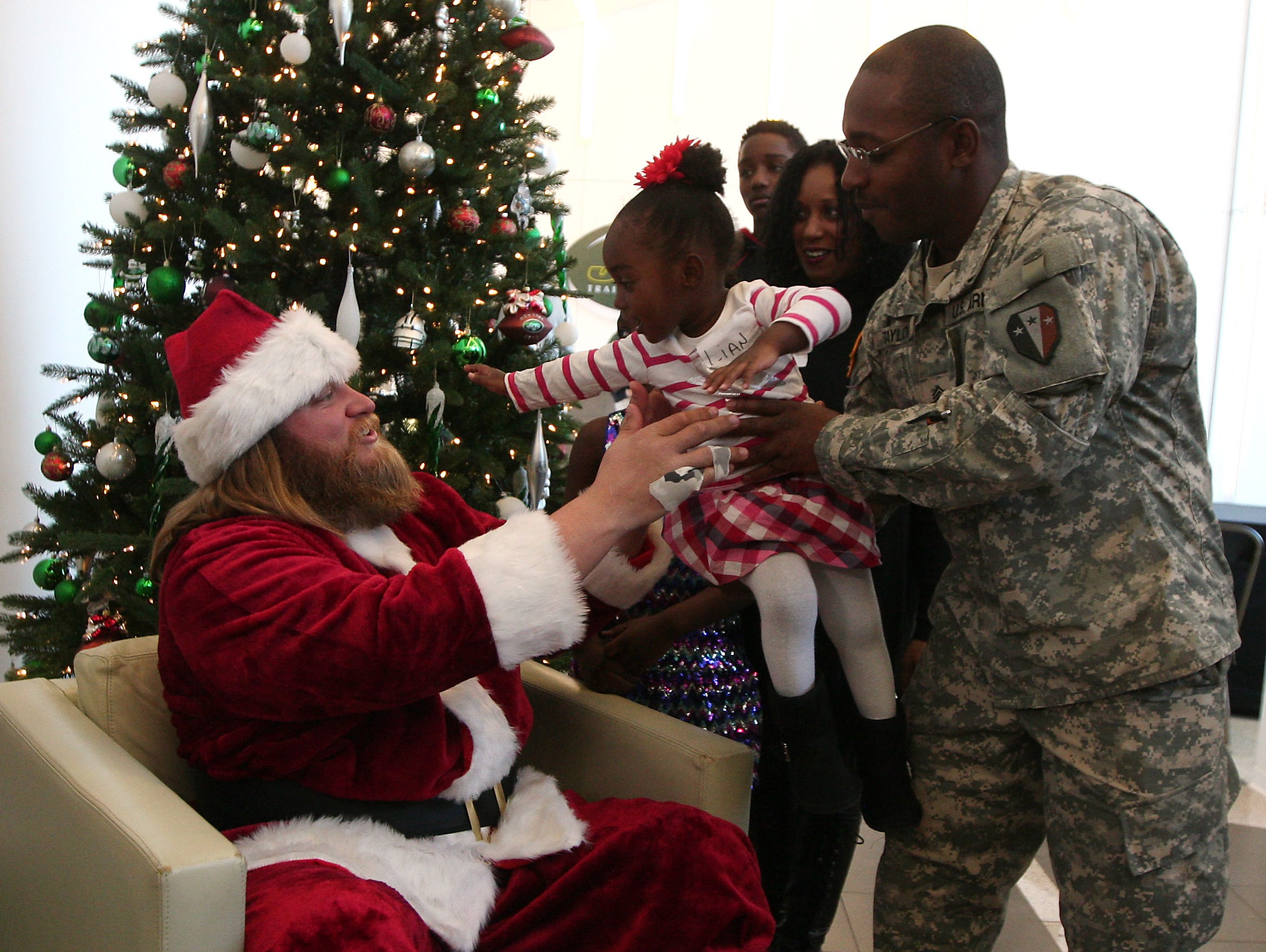 Donza Taylor of Bayonne hands over daughter 2-year-old Lian to Jets Pro Bowl center Nick Mangold as the New York Jets hosted a holiday party for military families at their Florham Park training facility. December 4, 2015, Florham Park, NJ.