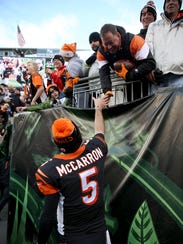Bengals quarterback AJ McCarron gives a football to