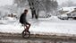 A boy rides a unicycle to school in the snow in Farmington,