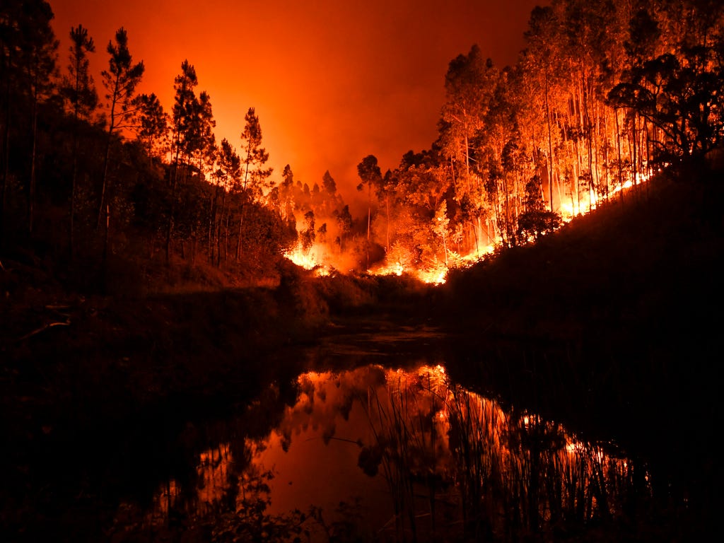 A wildfire is reflected in a stream at Penela, Coimbra, central Portugal, on June 18, 2017. The fire has killed at least 25 people and injured 16 others, most of them burning to death in their cars. Several hundred firefighters and 160 vehicles were 
