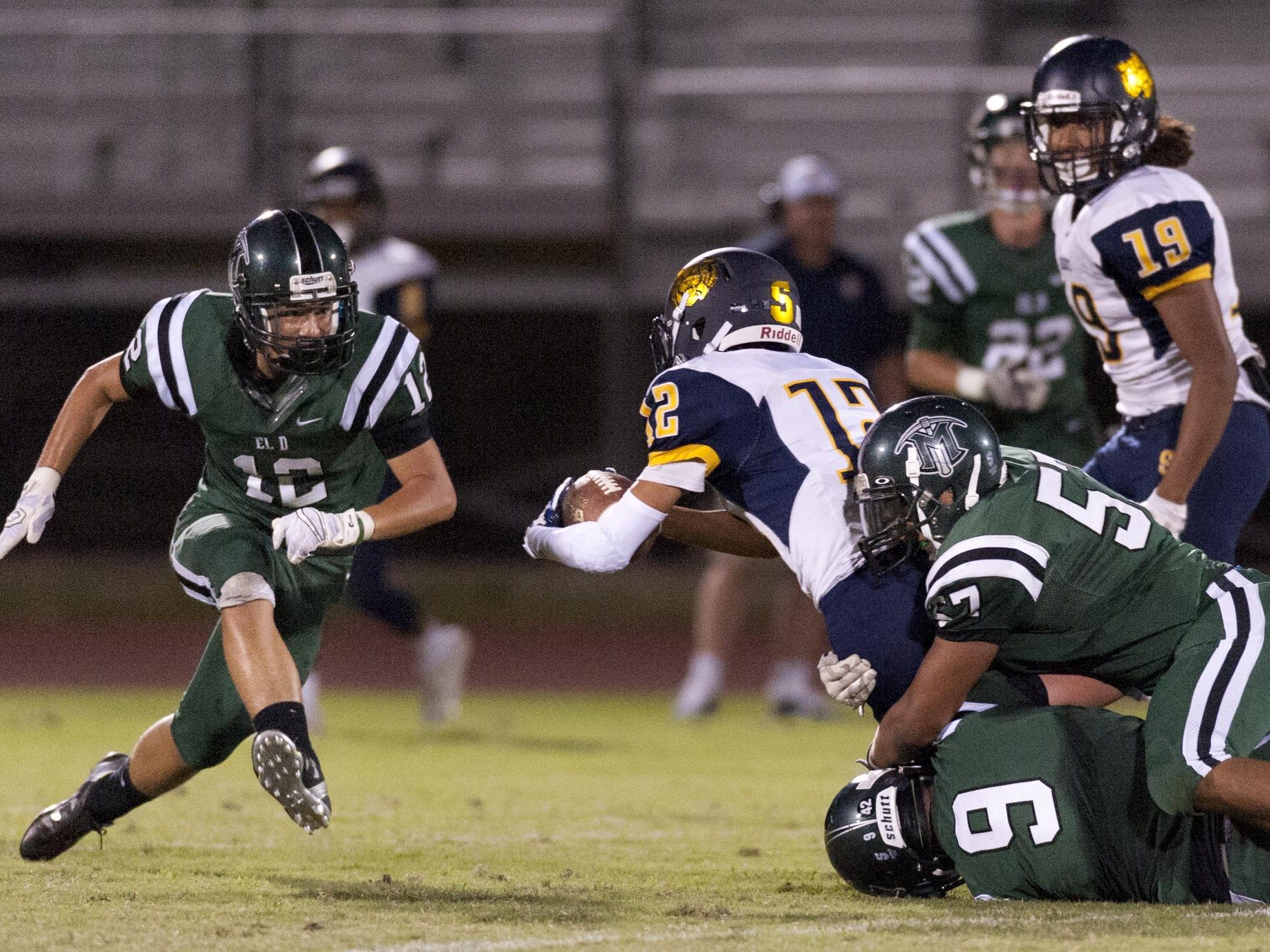 El Diamante’s Zach McCorvey rushes to assist Alec Pierce and Gerry Hernandez in taking down Sunnyside’s Raymond Hernandez in a Sept. 4 game.
