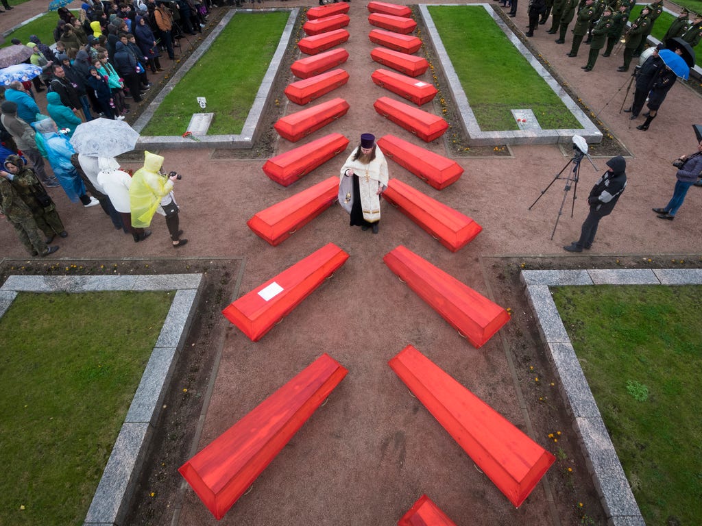 An Orthodox priest conducts a burial ceremony of Soviet soldiers killed during World War II who were discovered by members of volunteer search teams digging for remains on a former battlefield, in a memorial cemetery at Nevsky Pyatachok near Kirovsk,
