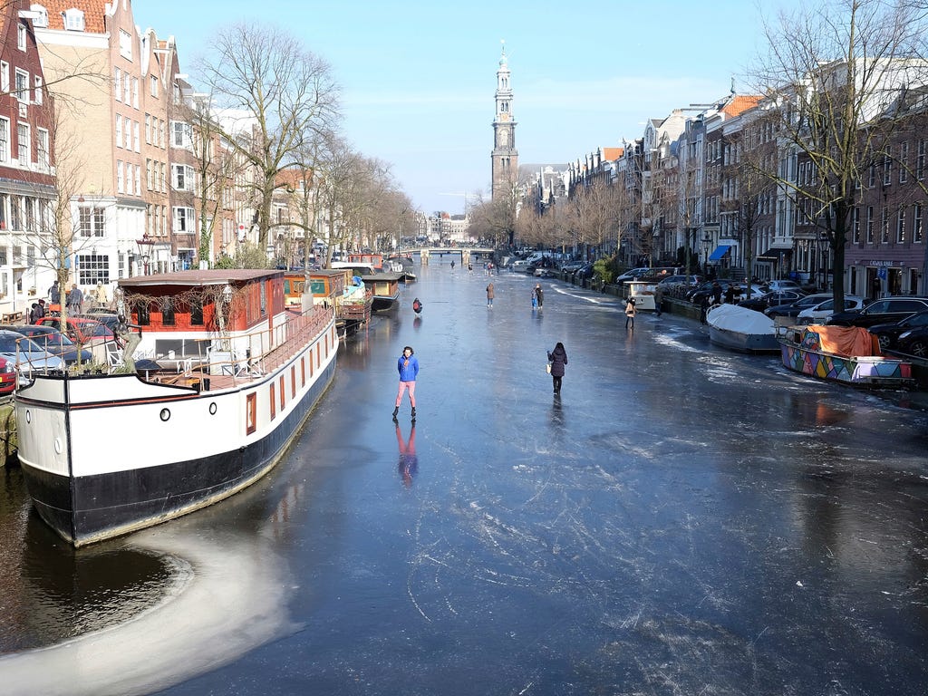 People walk and skate on the frozen Prinsengracht canal in downtown Amsterdam. The icy weather gripping much of Europe is good news for the Dutch, many of whom love to skate on frozen waterways.