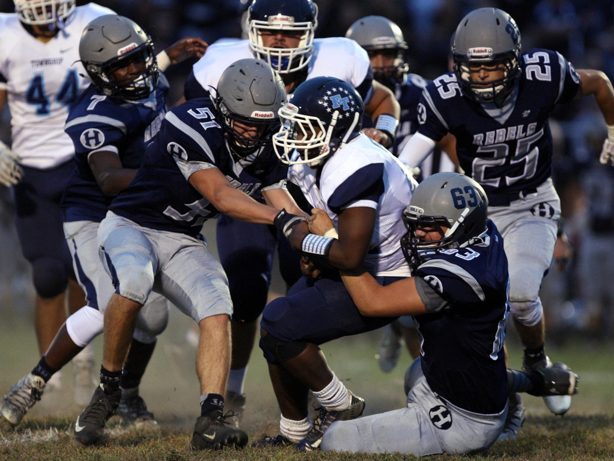 Rychard Hanshaw, #22 Freehold Township, is tackled by Conor Devine, #51 Howell, left, and Michael Ioannides, #63, right, and other defenders in a football game Friday, September 25, 2015, at Howell High School.