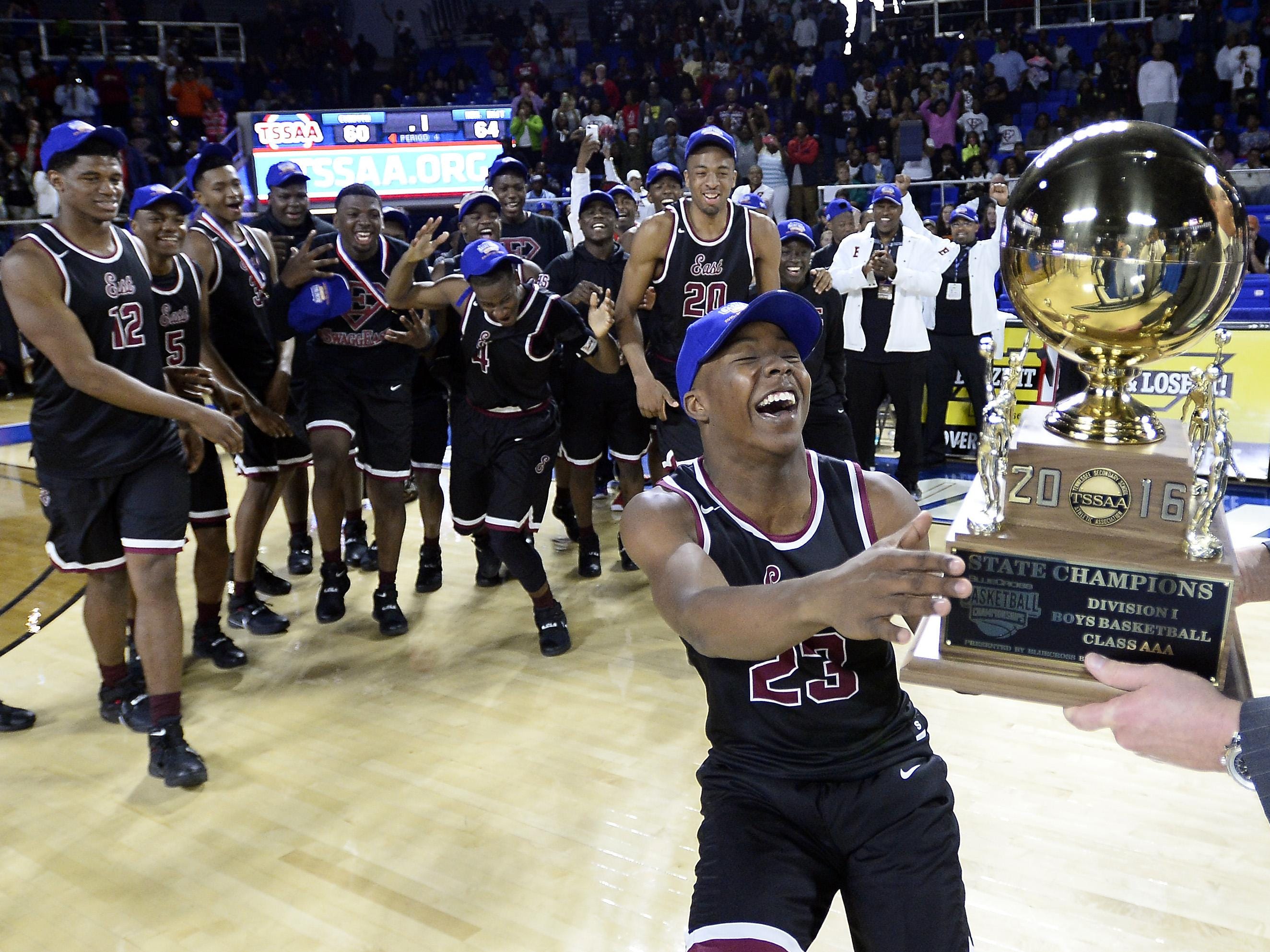 Memphis East’s Kobe Freeman (23) grabs the trophy as it is presented to the team after beating Cordova in the Class AAA championship on Saturday.
